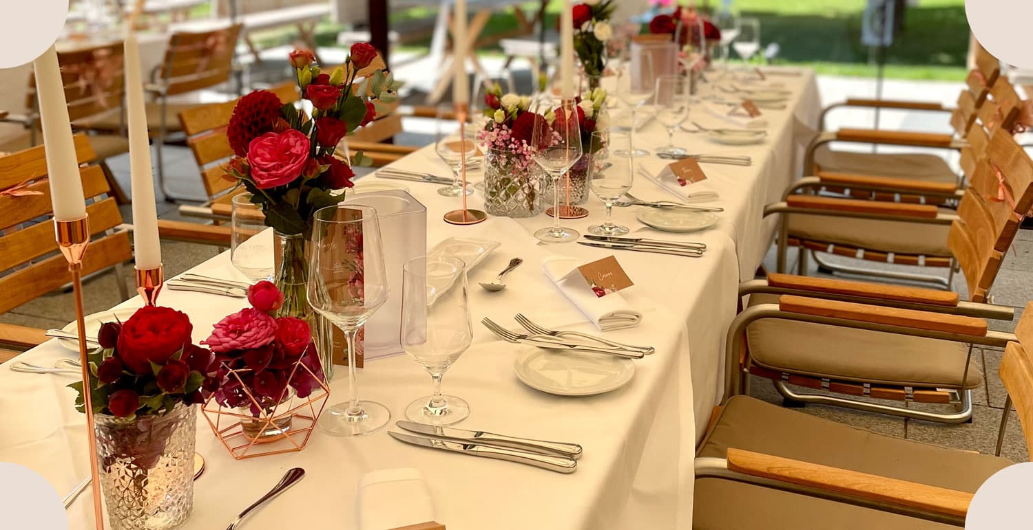 Hochzeitsdekoration und Floristik an einer langen Tafel in weiß und rot