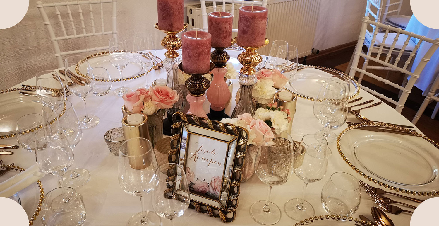 Tischedekoration mittig mit rosanen Kerzen, Rosen und Platzkarten