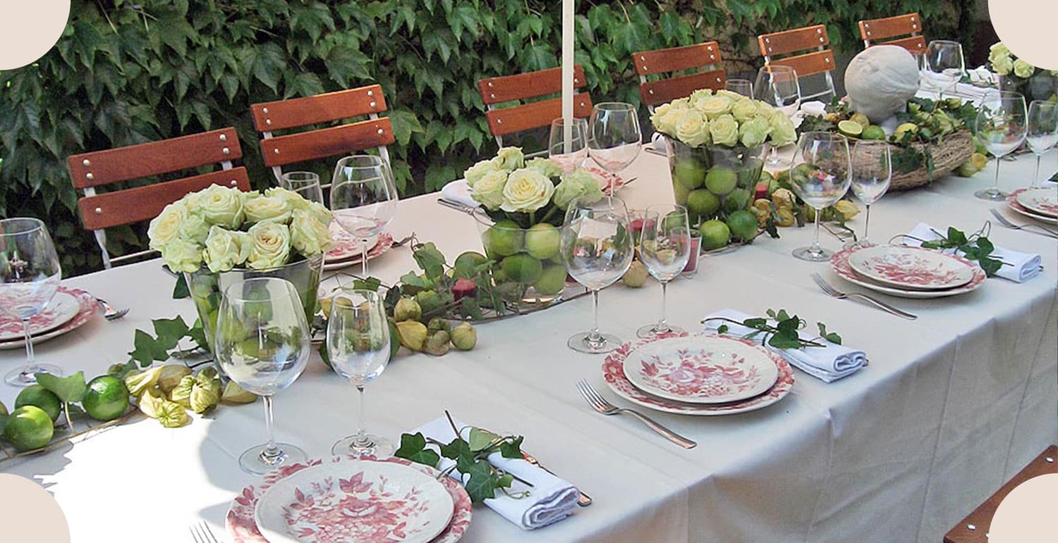 Hochzeitsgedeck an einer langen Tafel mit weißen Rosen und Zitrusfrüchten